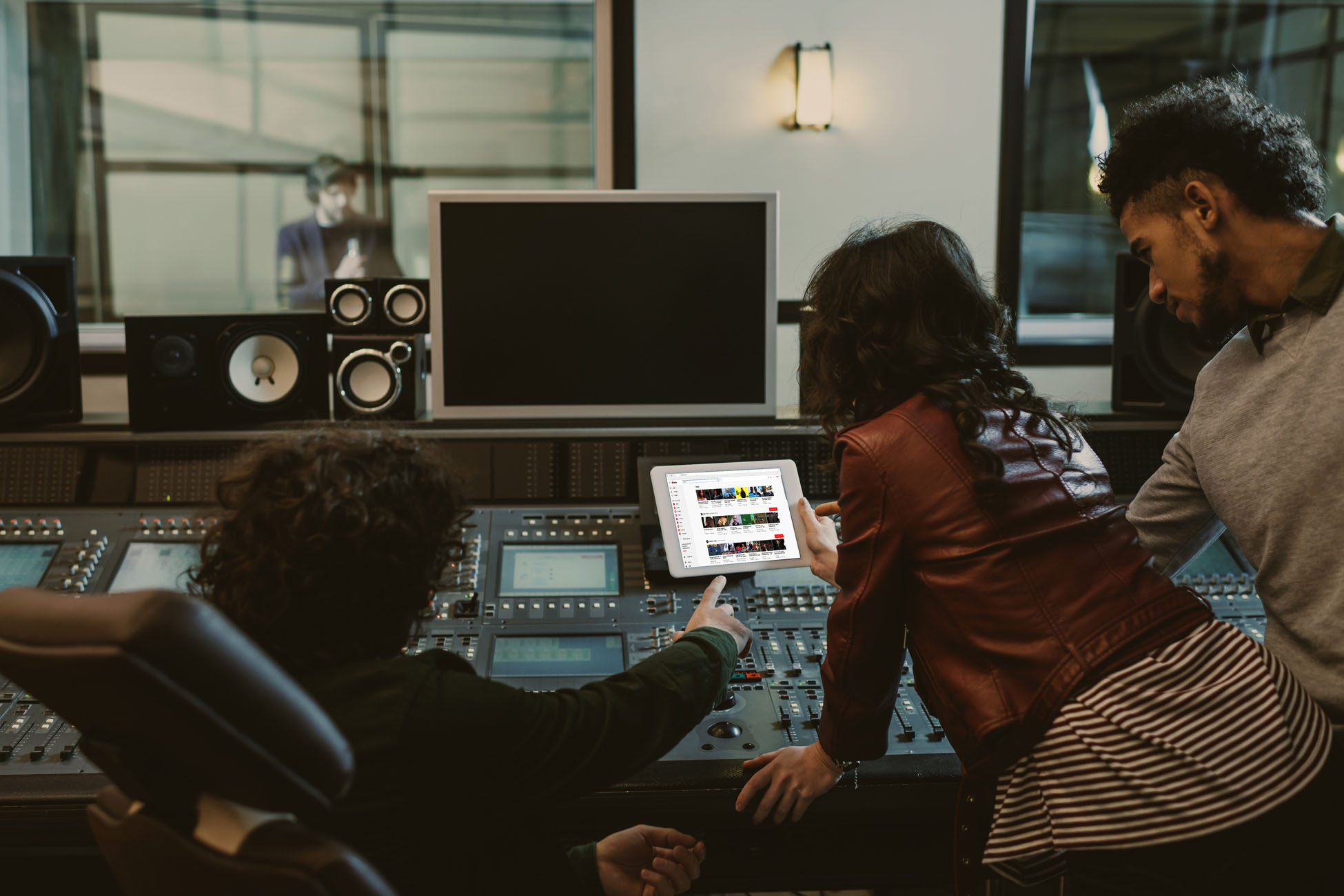 sound producers using tablet together at recording studio with youtube website on screen
